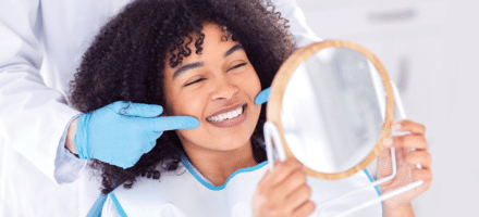 Woman holding a mirror getting a dental cleanings in Anchorage.