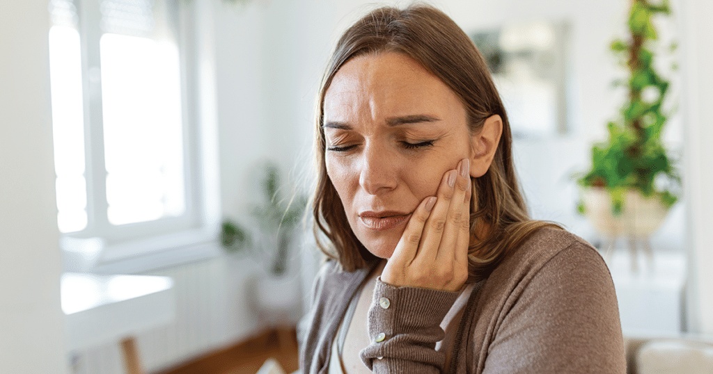 Woman holding her jaw wincing with pain.