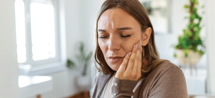 Woman holding her jaw wincing with pain.